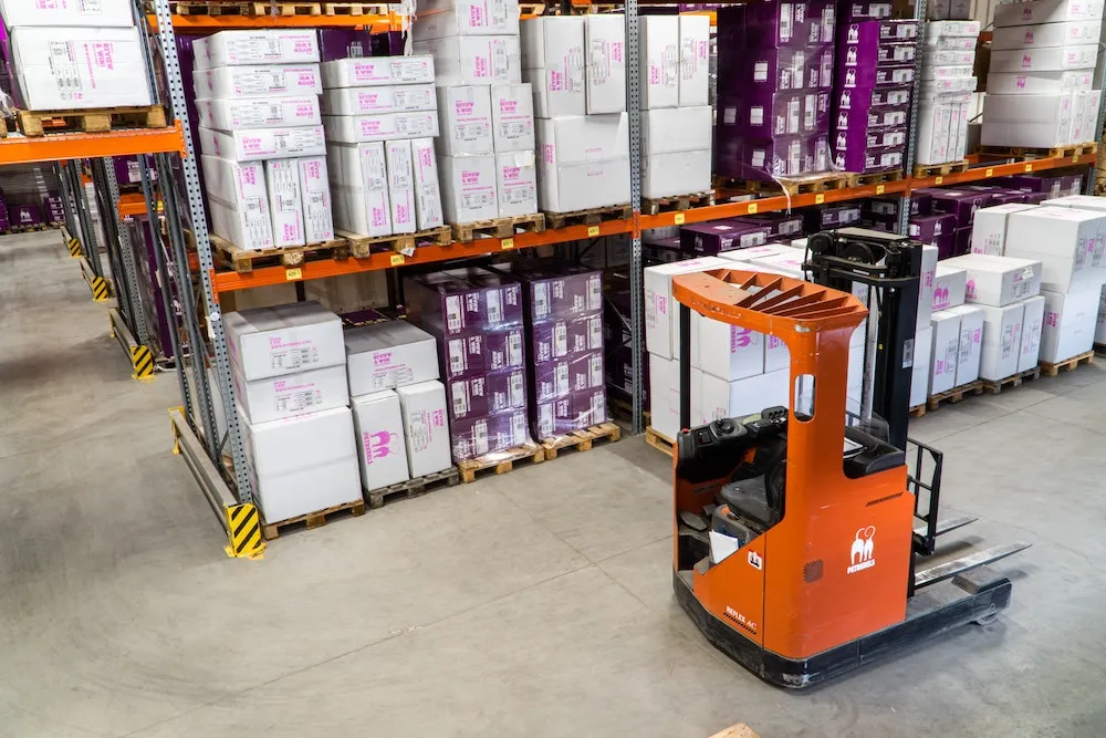 Forklift parked in a warehouse in front of shelves full of inventory.